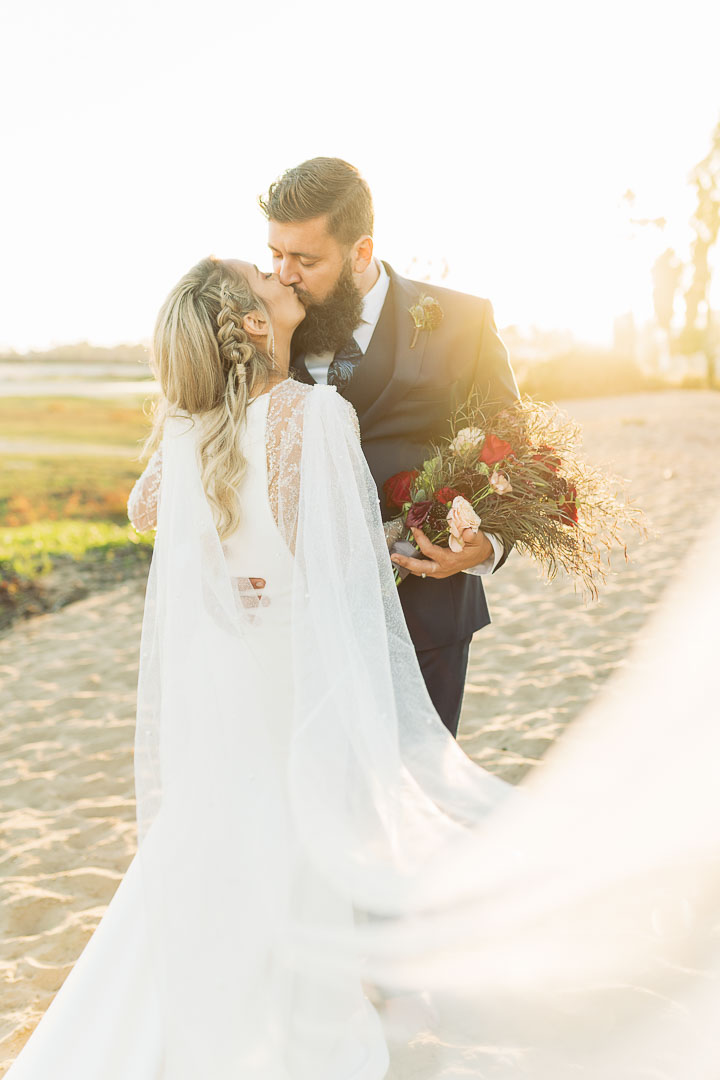 Bride and Groom taking charming, warm couple photos at golden hour on their wedding day at East Beach across from their wedding venue at the Santa Barbara Carousel House.